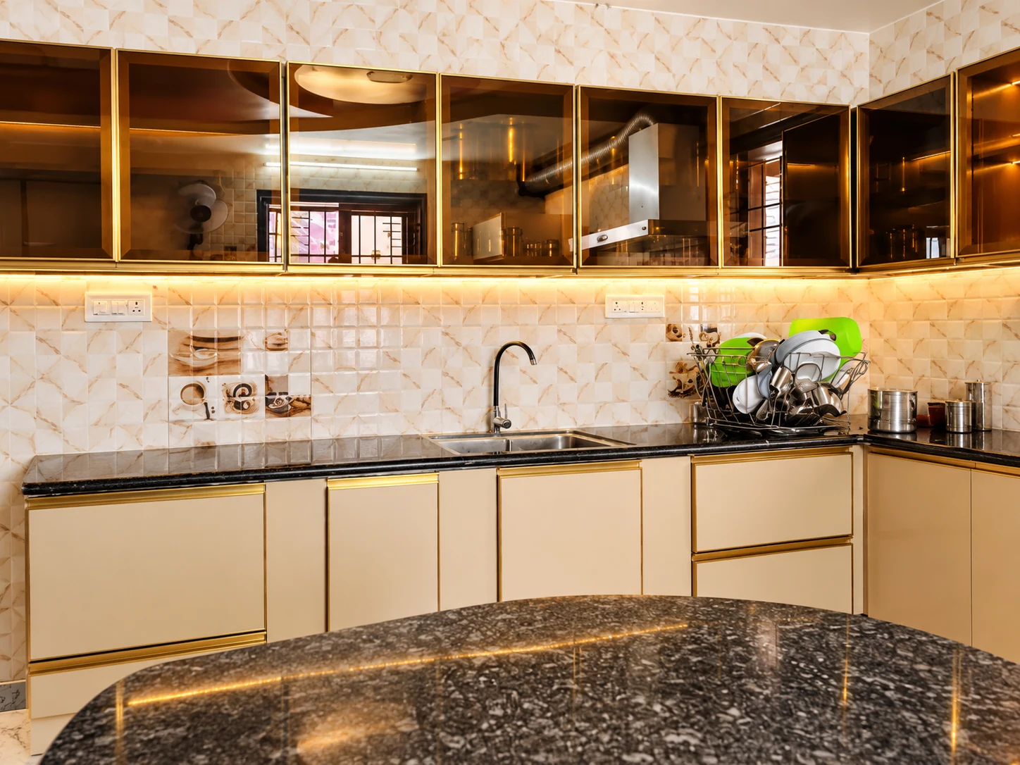 Cream and gold kitchen cabinetry with dark countertop and glass overhead cabinets